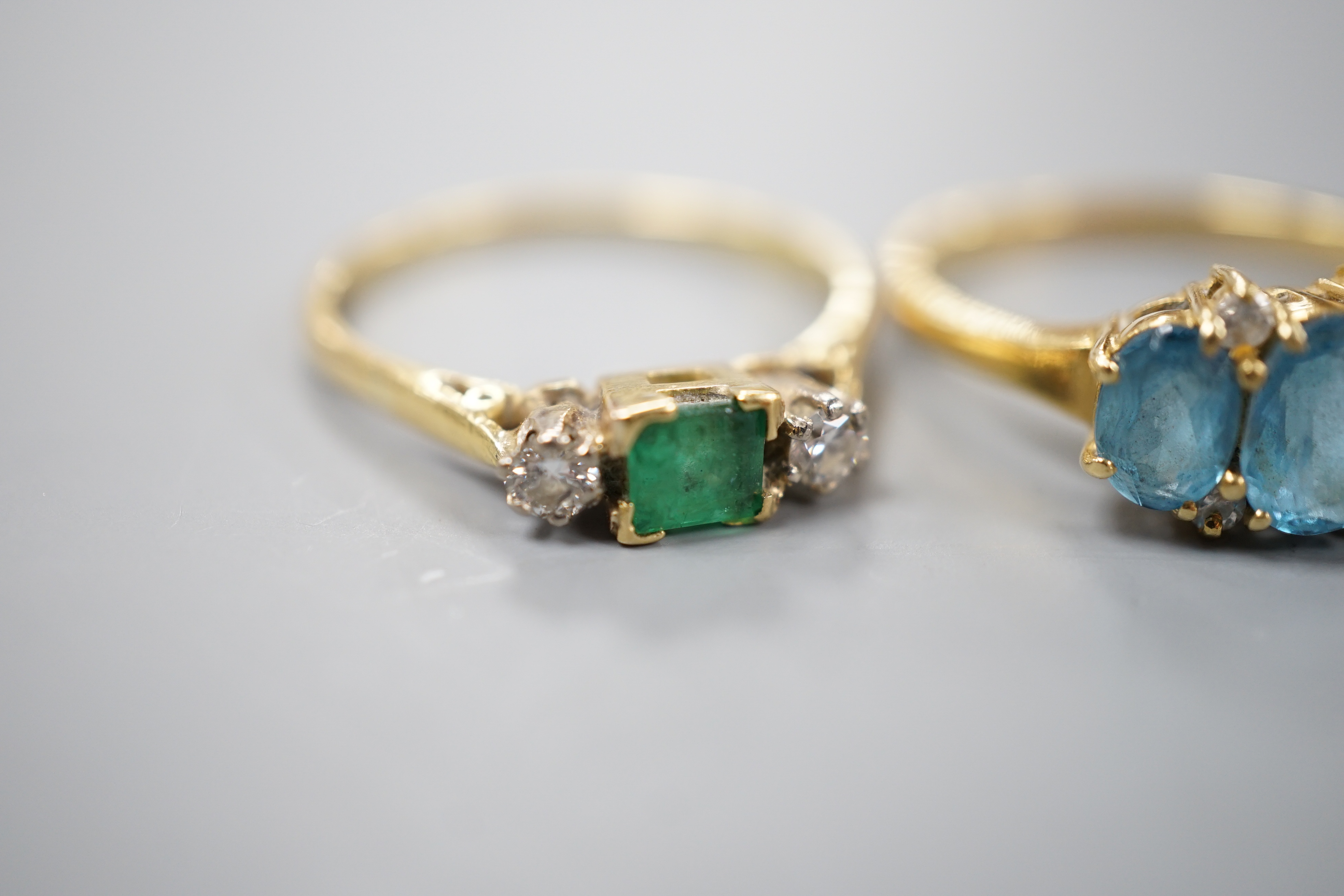 Three assorted 18ct and gem set dress rings, including emerald and diamond three stone, size Q/R, gross 11.7 grams.